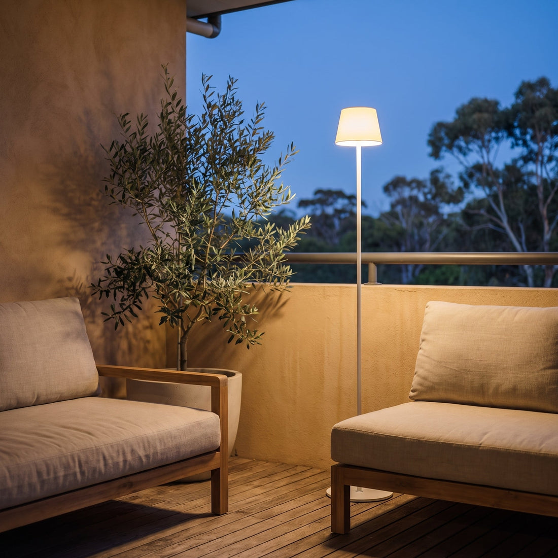 A cordless floor lamp glowing warm on a covered Australian balcony at dusk