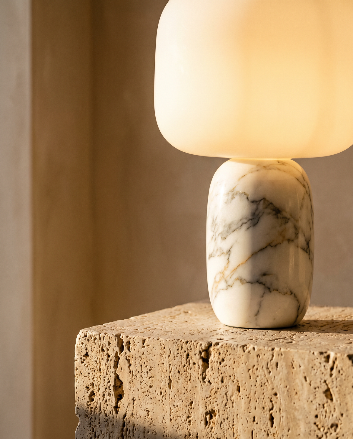 Marble-base cordless lamp on a travertine plinth in warm evening light