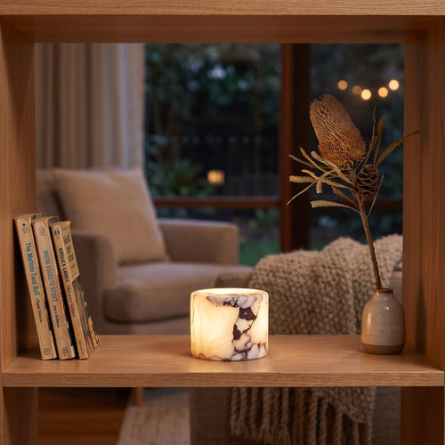 Agata white marble cordless night light glowing on a timber shelf beside books in the evening