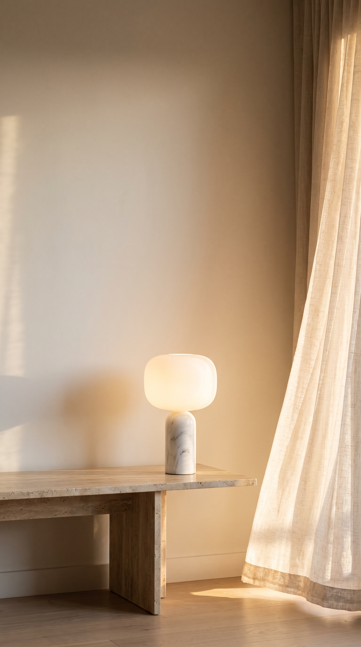 Cordless marble Las Noche lamp glowing on a travertine bench in warm evening light