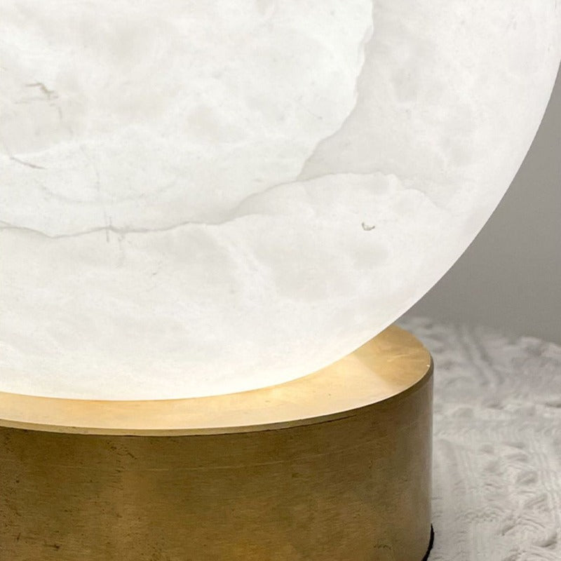 Detail of the solid brass cylinder base under the glowing alabaster sphere of the Luna lamp